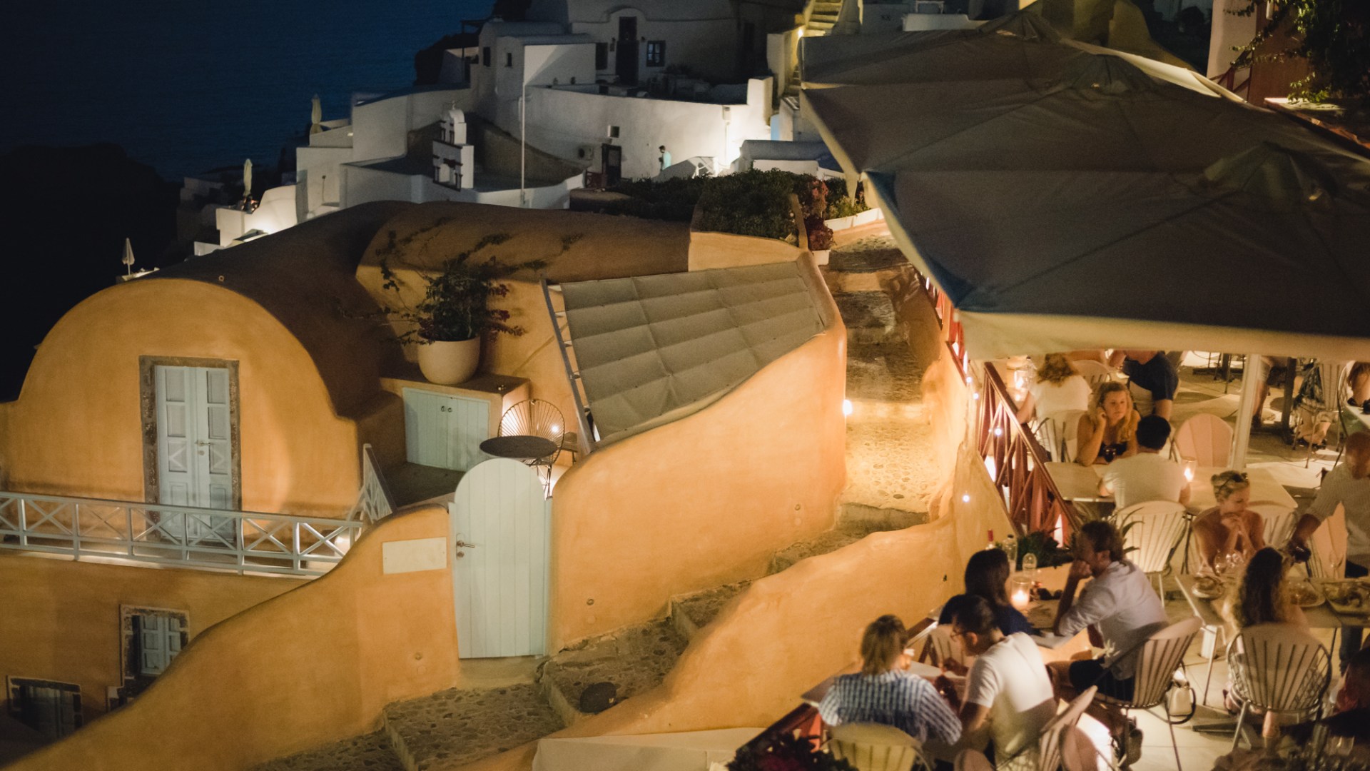Restaurant in Santorini, Oia. People enjoining their meal at twilight.