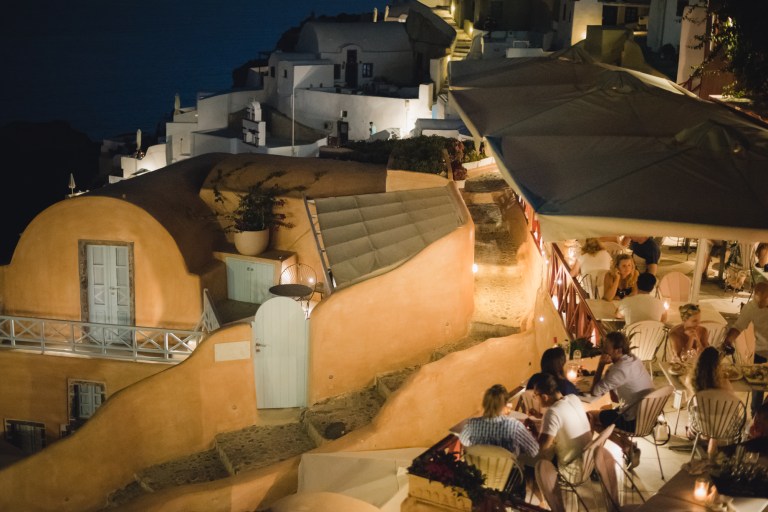 Restaurant in Santorini, Oia. People enjoining their meal at twilight.