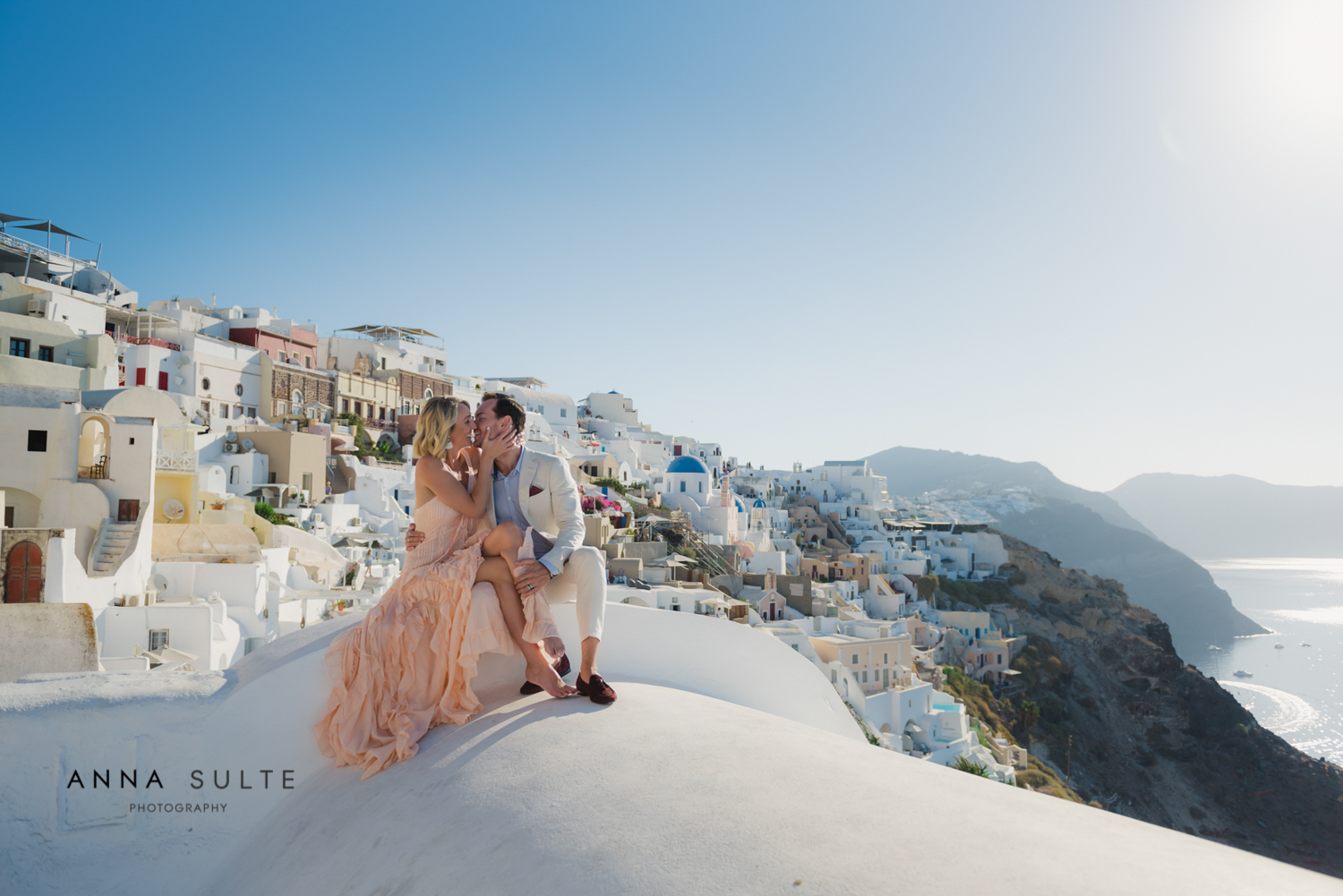 Couple sitting, iconic Greek view behind them