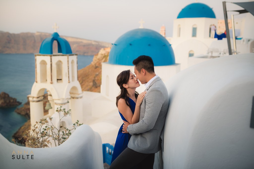 Greece photoshoot. Blue churches and a couple hugging.