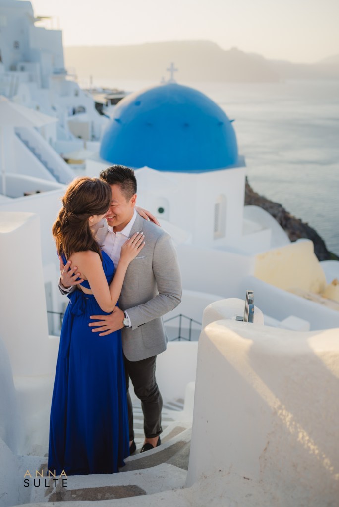Couple standing in front of blue dome, Santorini.