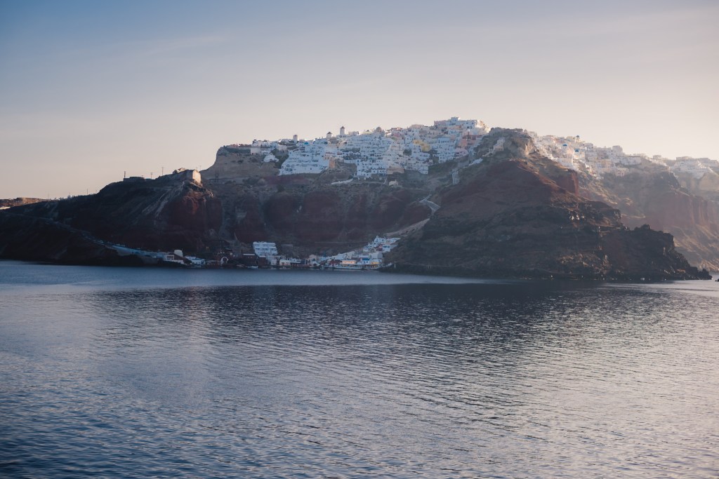 Oia view from the ocean. Backlit white washed village. Santorini, Greece.