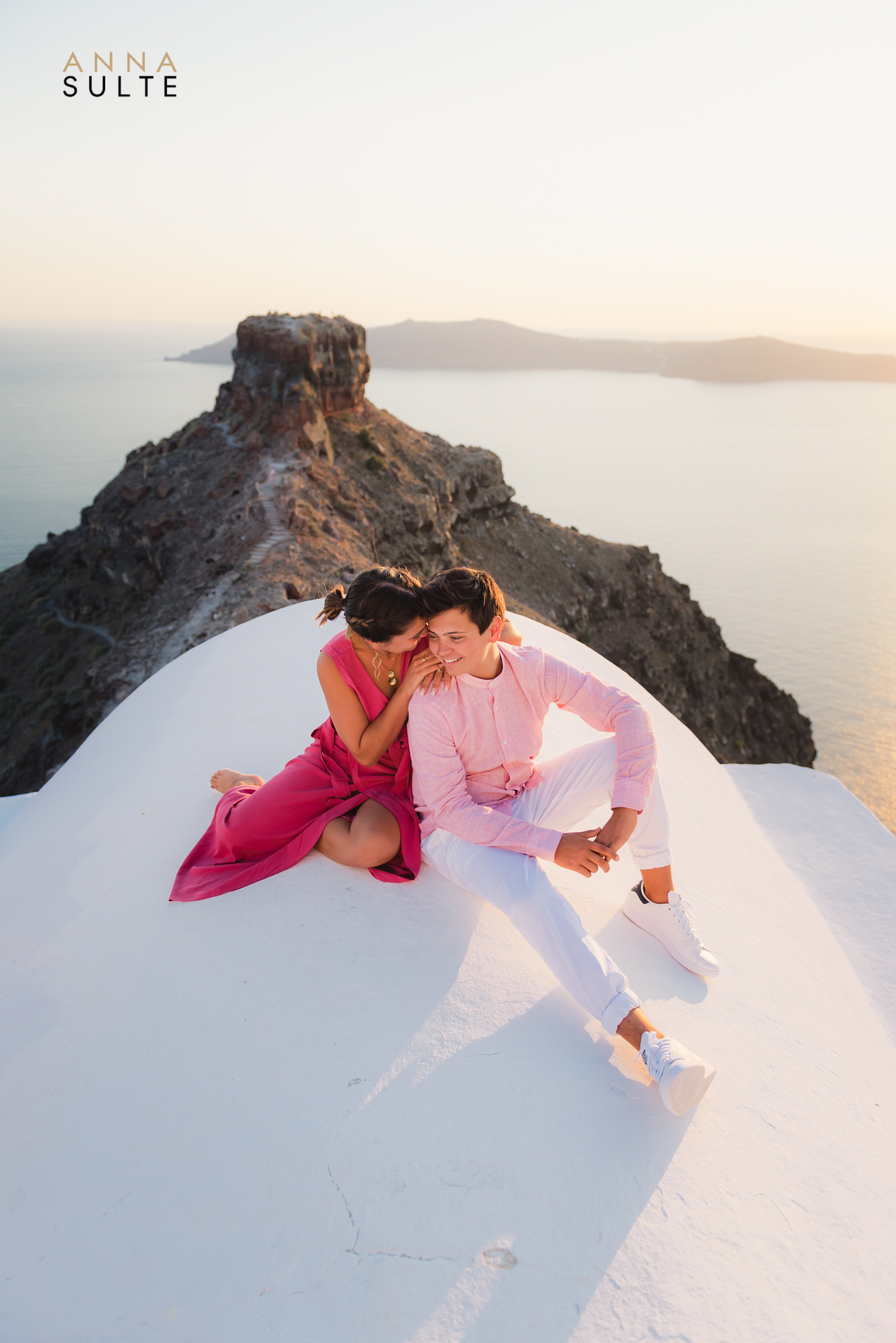 couple sitting on the white roof in Santorini. Sunset engagement shoot.