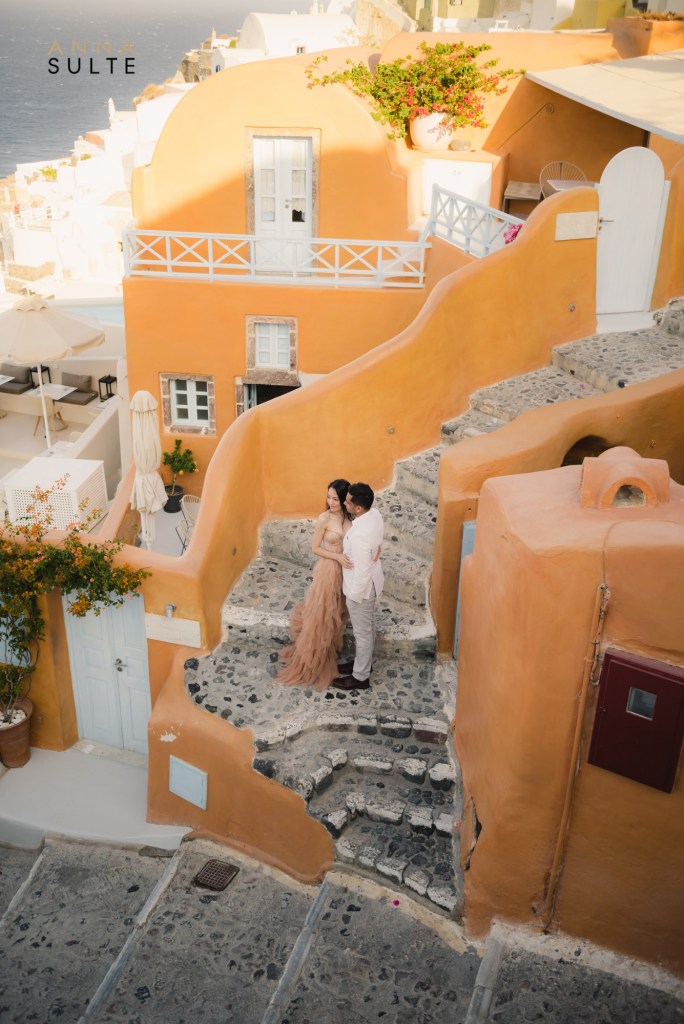 Couple on the steps, next to terracotta houses in Oia, Santorini