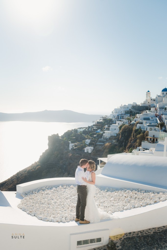 Santorini photoshoot, couple in their wedding attire on the rooftop with a view.
