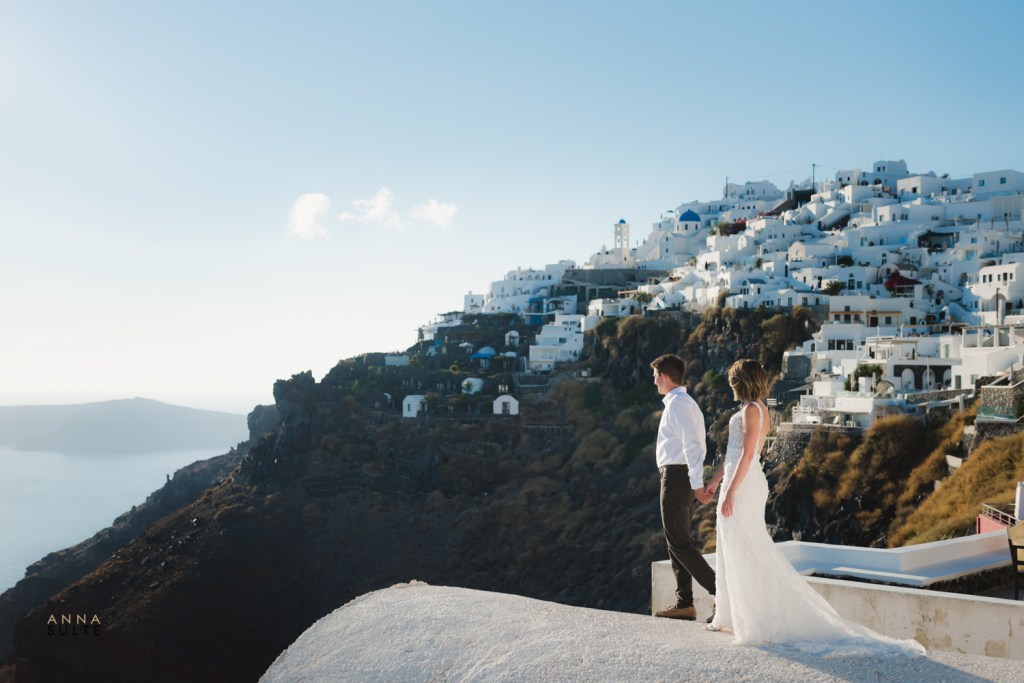 Just married couple holding hands while walking on a rooftop with a breathtaking island view.
