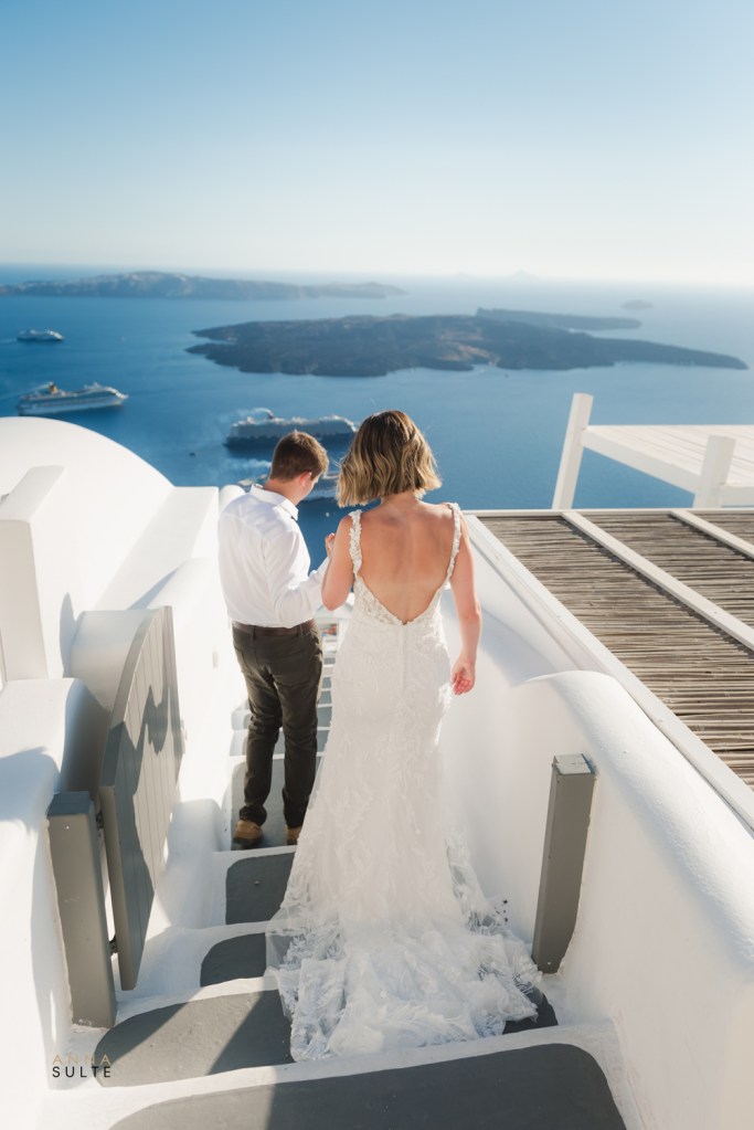 Couple walking down the steps, her wedding dress is behind her.