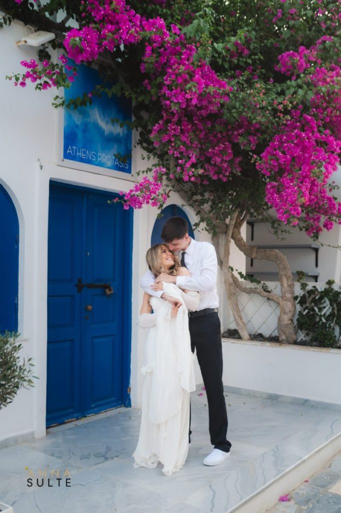 Bride and groom sharing a kiss in front of the picturesque blue doors of Santorini, Greece.