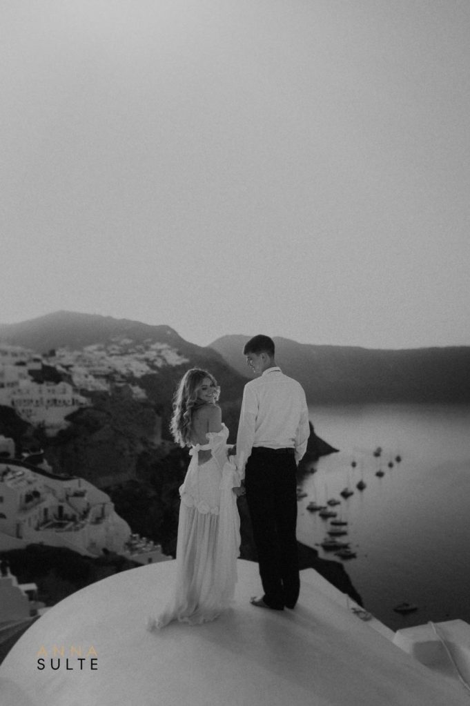 Elopement in Santorini: A couple embraces on the caldera cliffs with a stunning ocean backdrop.
