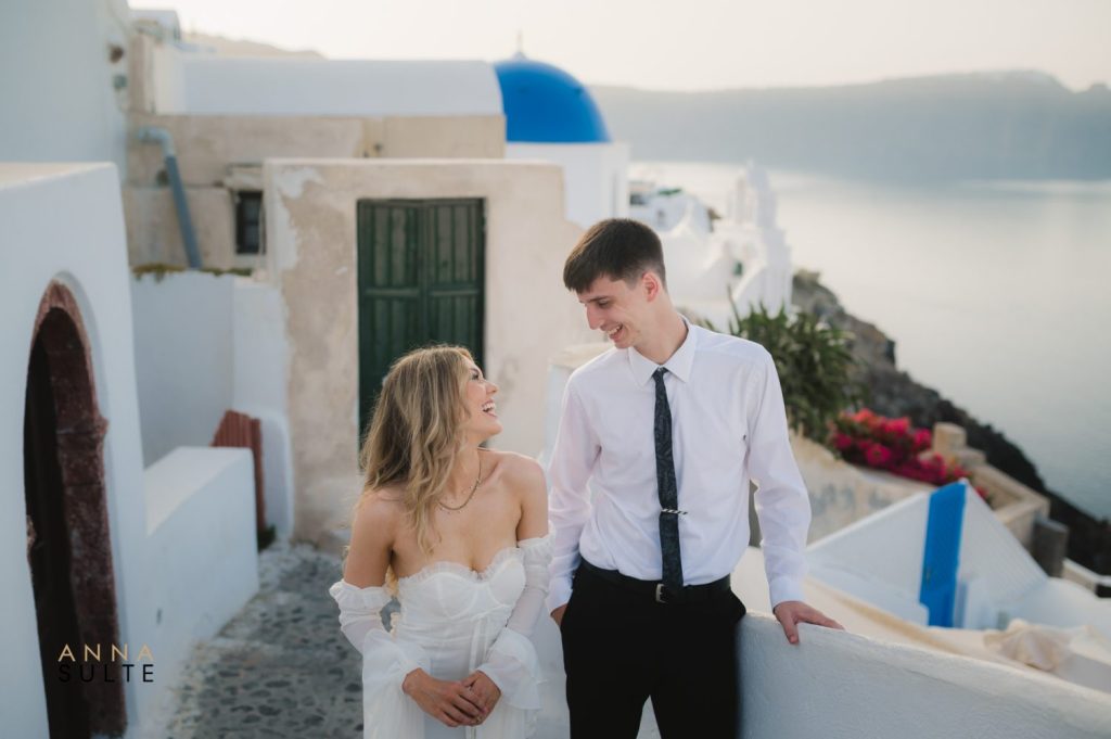 Candid laughter between a couple, capturing pure joy in Santorini’s iconic white-washed alleys.