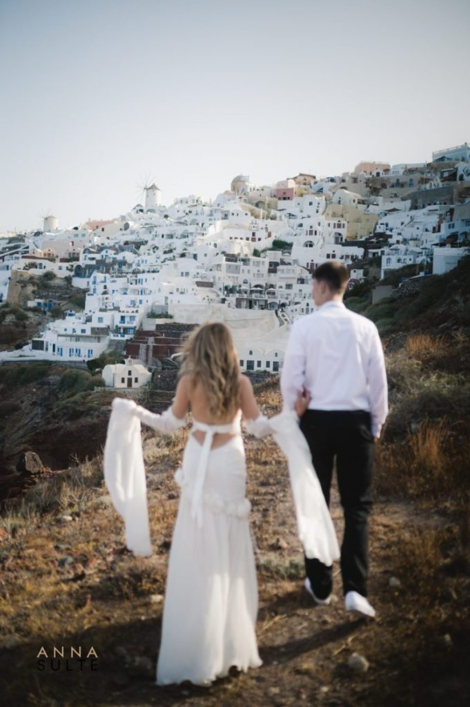 Romantic moment of a couple walking away into the Santorini sunset.
