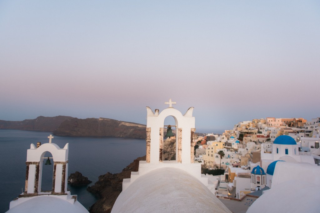 Oia churches in Santorini, Greece. Two bell towers and white washed village behind.