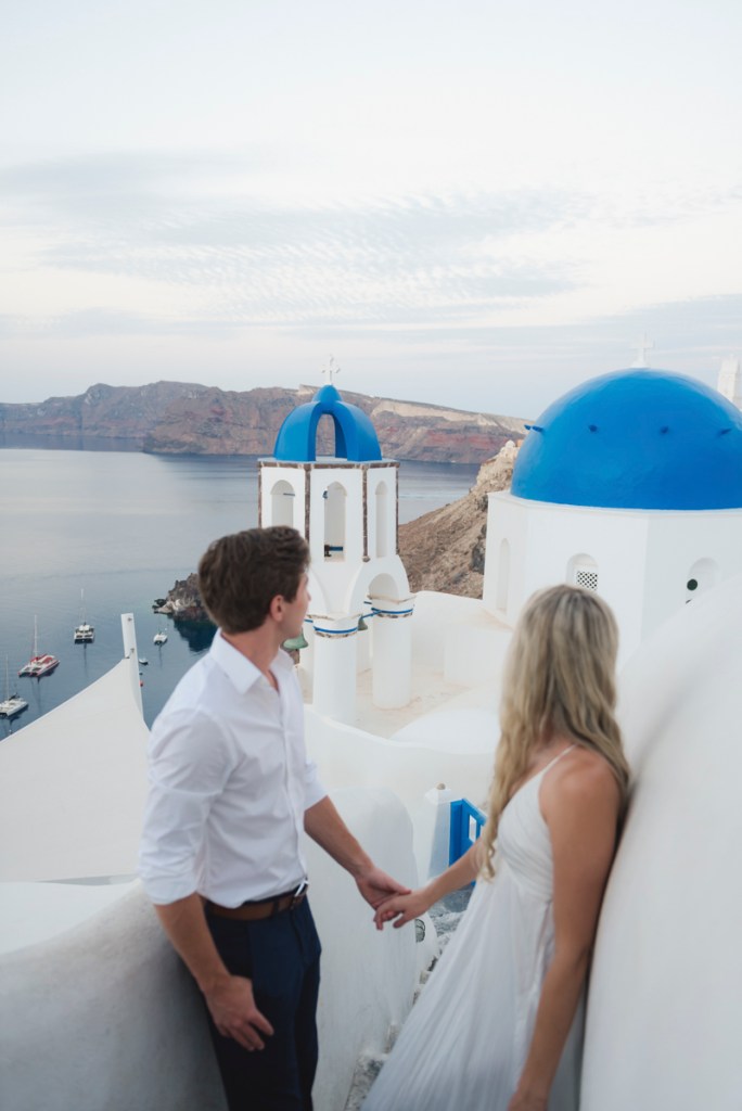 A couple standing and looking at the Oia blue domes 