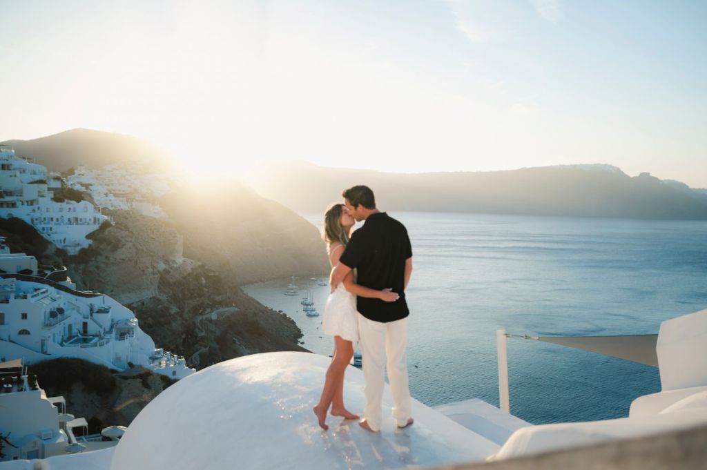 Honeymoon photos in Santorini Greece at sunrise, Oia streets with blue domes, captured by professional Santorini engagement photographer.
