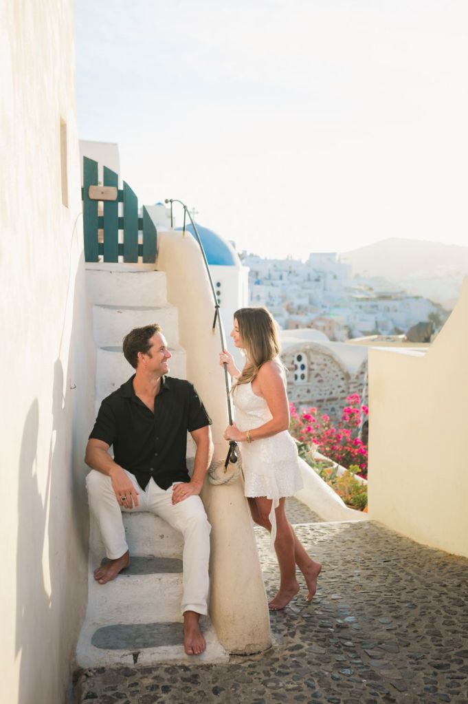 Couple on the steps in Oia Santorini at sunrise with iconic blue dome, captured by a professional Santorini photographer.