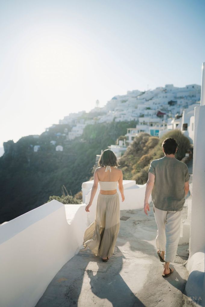 An intimate couple photoshoot in Imerovigli during sunset, featuring wide caldera views, soft colors, and the peaceful energy of Santorini evenings.