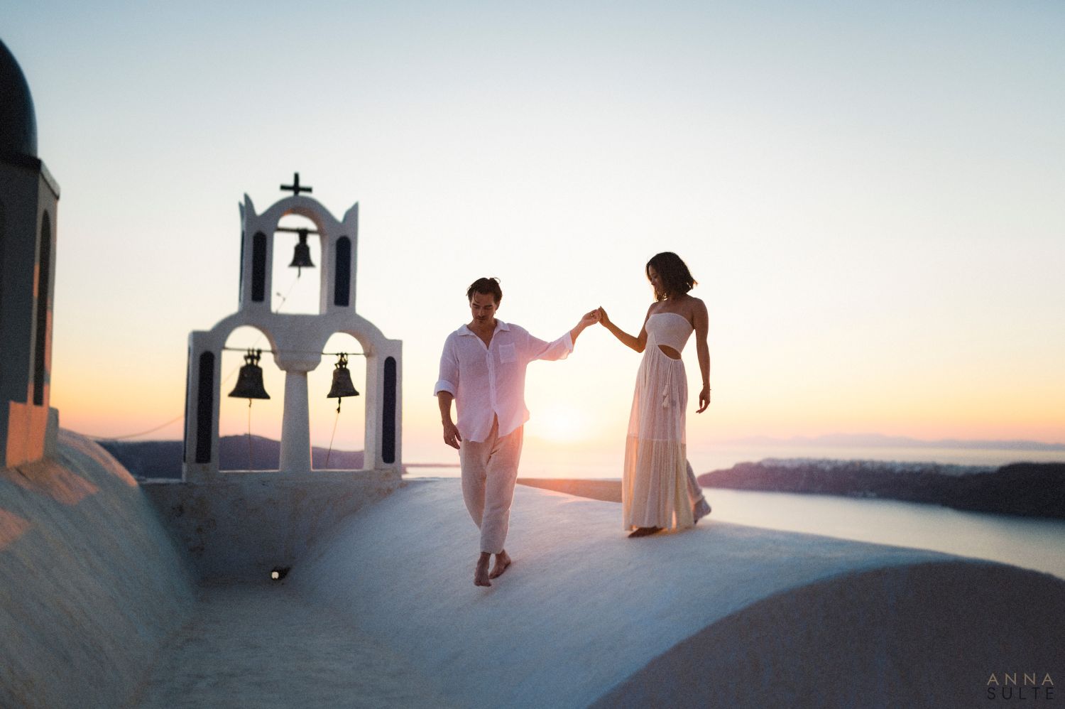 Santorini Photo Shoot at sunset in Imerovigli. Couple walking on a rooftop.