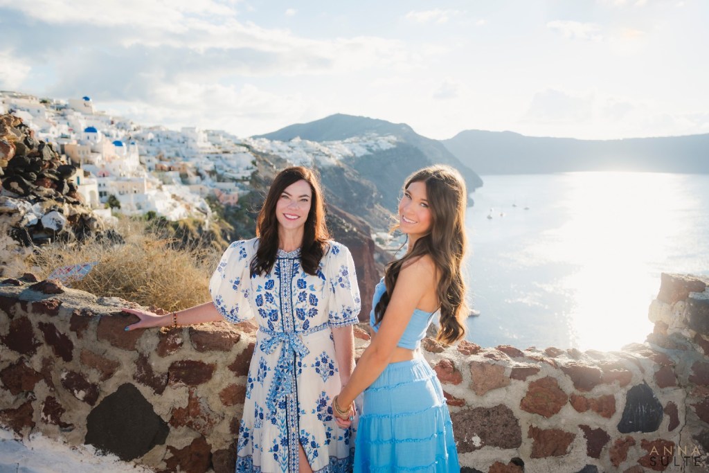 Teen girl with mom candid laughter gainst Santorini cliff side