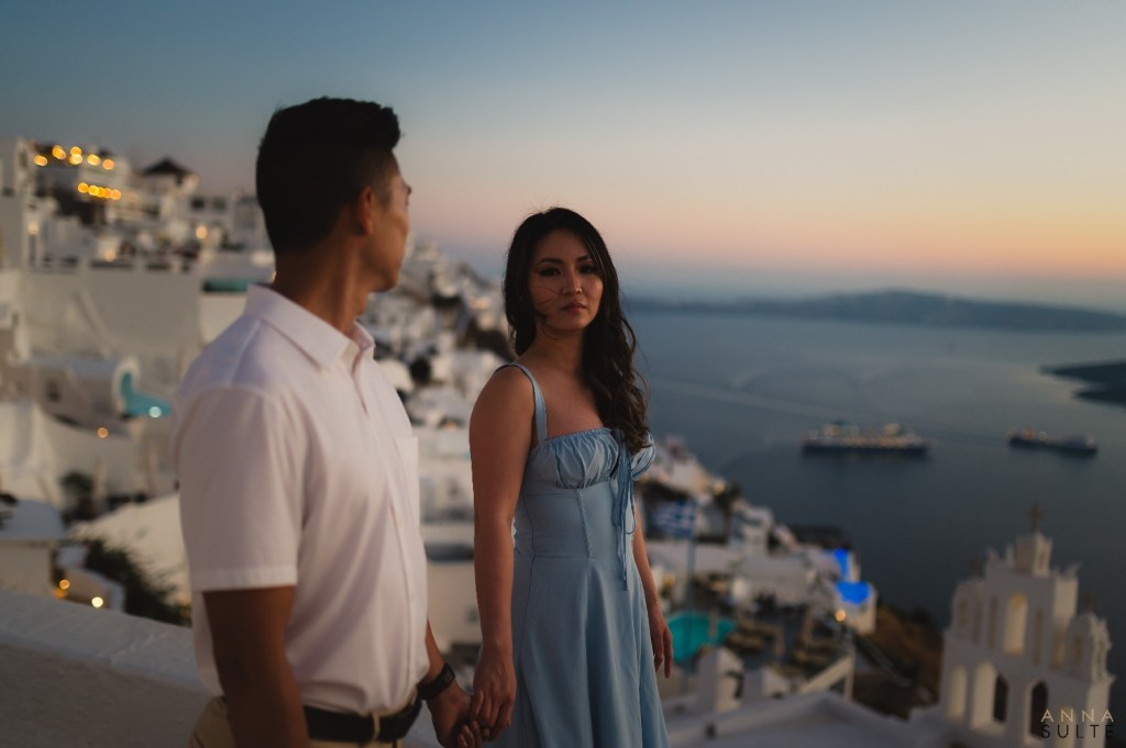 Couple sharing a candid moment on a terrace overlooking the caldera in Santorini.