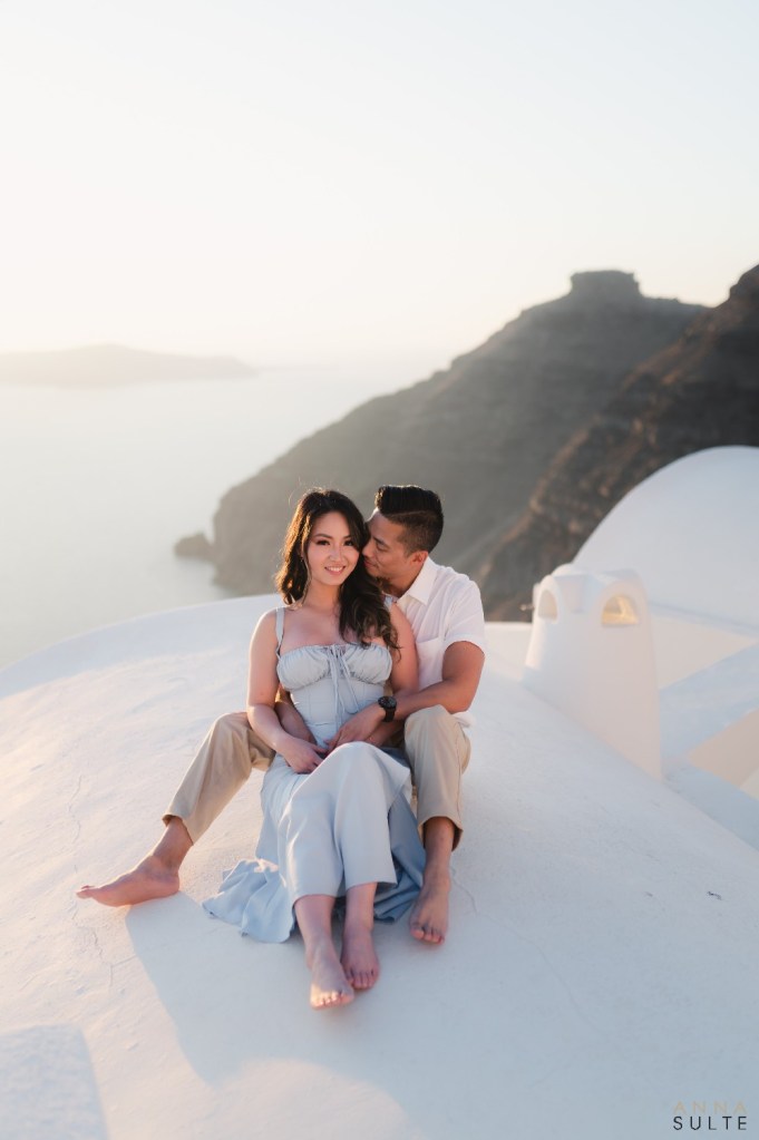 Relaxed couple seated on terrace enjoying sunset views during a natural Santorini photoshoot.