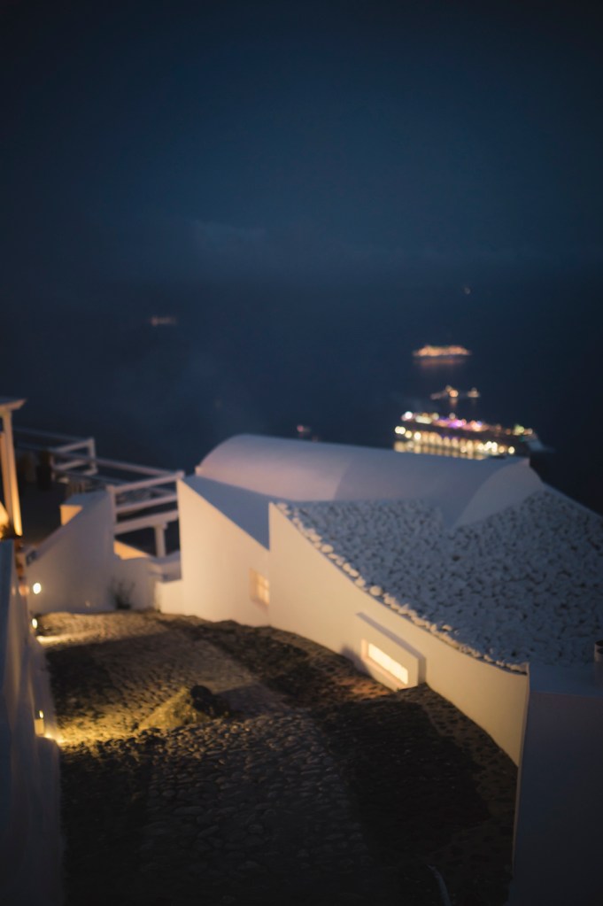 City lights in Santorini. Steps leading down. View of white washed buildings and cruise ships.