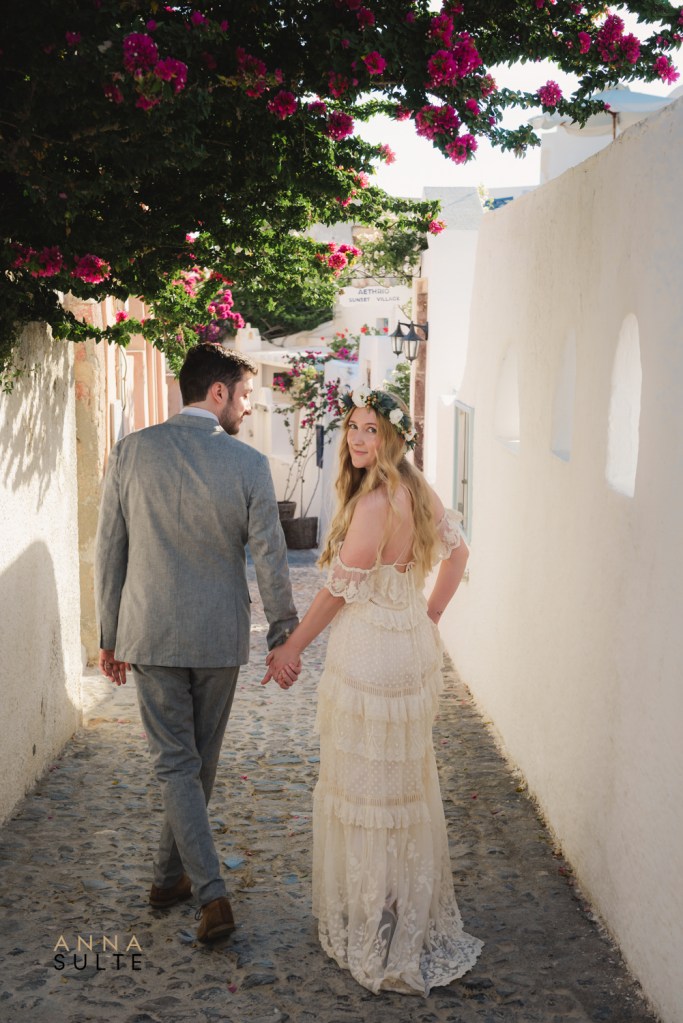 Romantic Santorini couple photoshoot in Oia with a couple walking through white streets