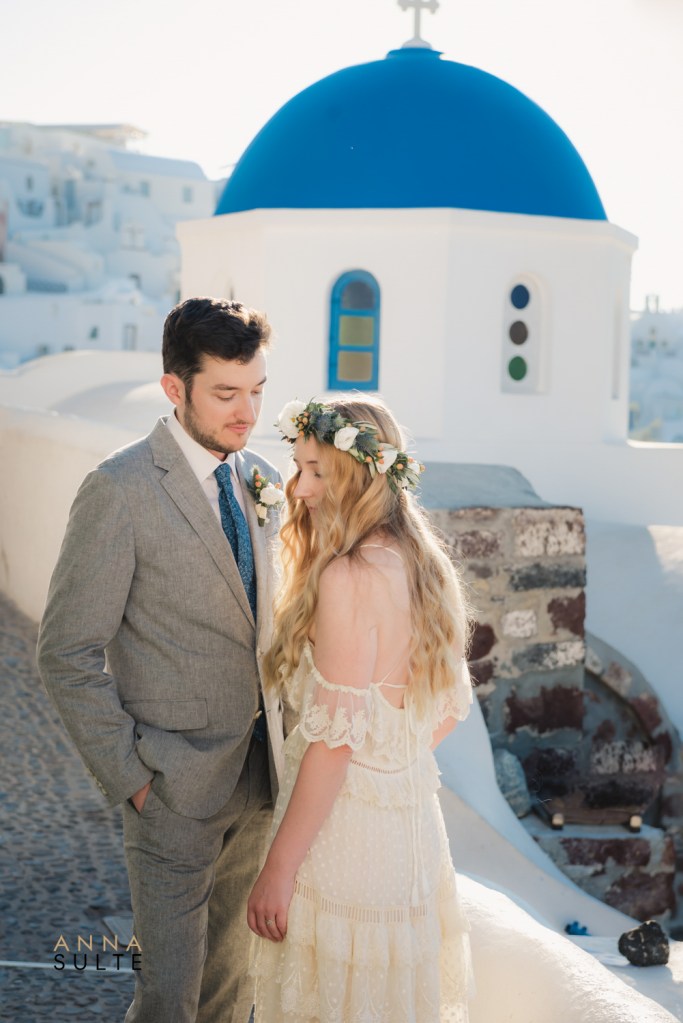 A couple posing near the famous blue domes during their Santorini couple photoshoot